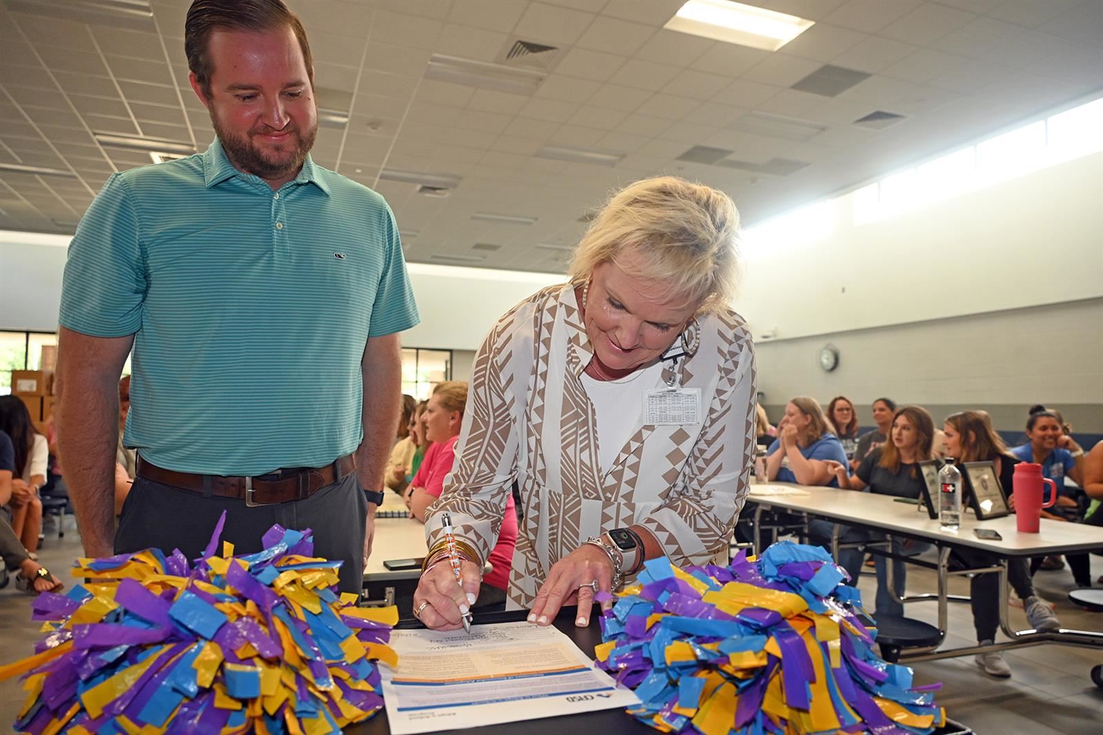 Sage Papaioannou, Hamilton Elementary School principal, signs an Adopt-a-School partnership agreement.